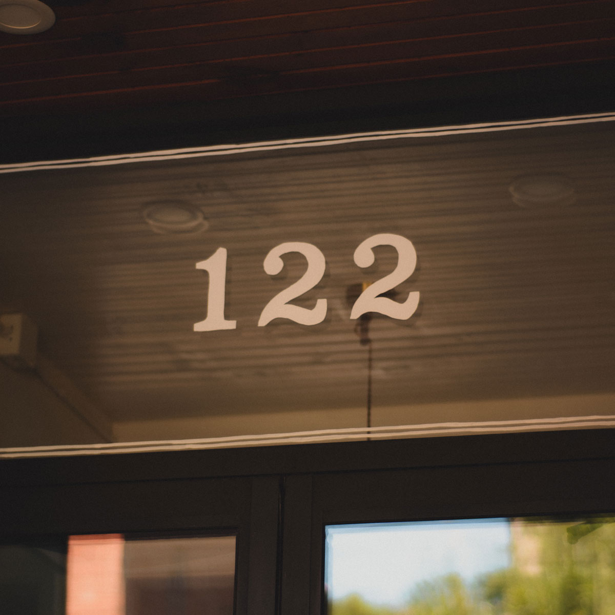 Hand-lettered address number 122 on a transom