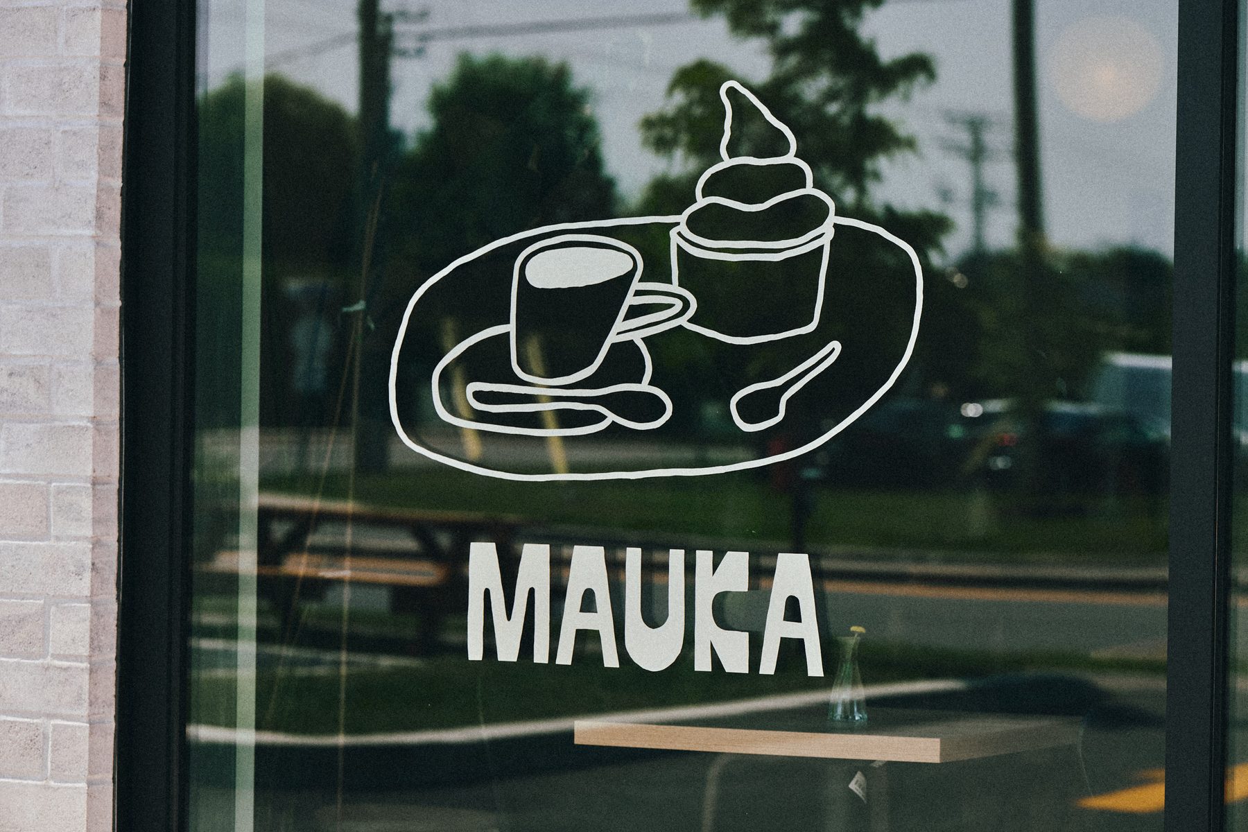 Hand-painted Mauka logotype and coffee-and-ice-cream illustration on the café window
