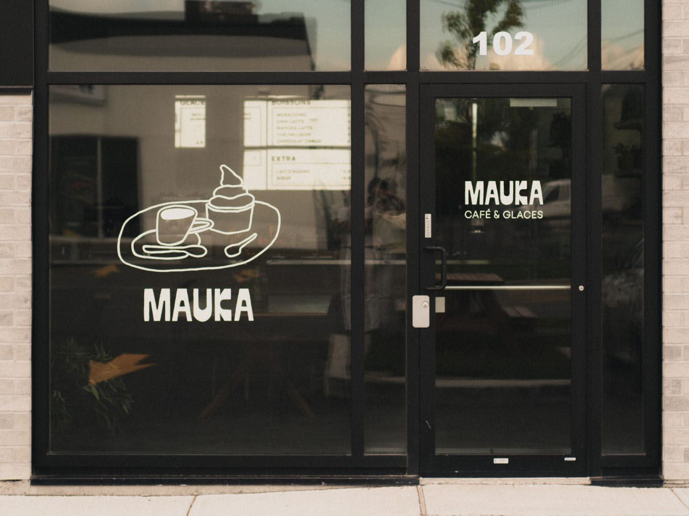 Mauka Café & Glaces storefront with hand-painted window graphics at dusk